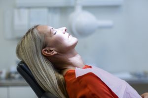 Blonde-haired woman relaxing in a dental chair after receiving sedation