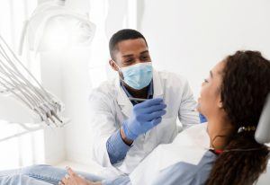 dentist holding dental tool speaking to patient in dentist chair