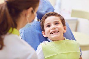 child in dental chair smiling at dentist